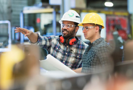 Two workers in hard hats looking at something off camera.