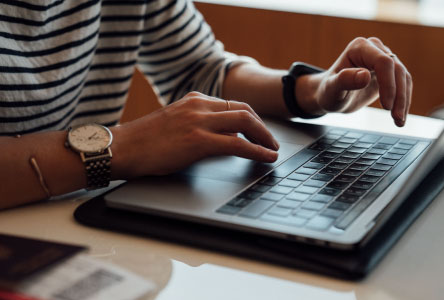 Close up of a person's hands hovering over a laptop keyboard.